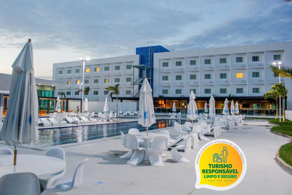 un hotel con mesas y sillas y una piscina en Bristol Aline Alagoas, en Delmiro Gouveia