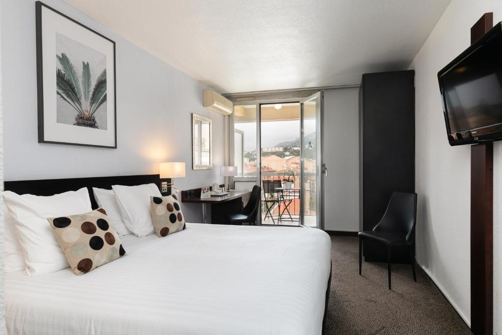 a hotel room with a bed and a desk and a television at Best Western Hotel Mediterranee Menton in Menton
