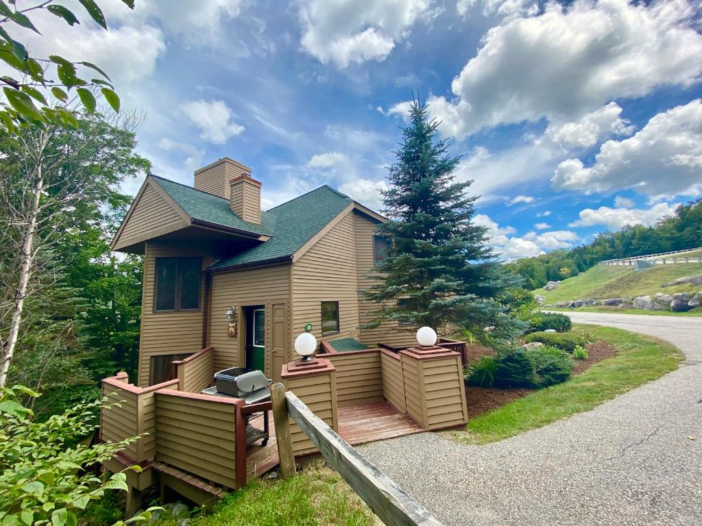 una casa con terraza y un pino en C4 Beautiful, homey slopeside townhouse for your family getaway in the heart of the White Mountains!, en Carroll