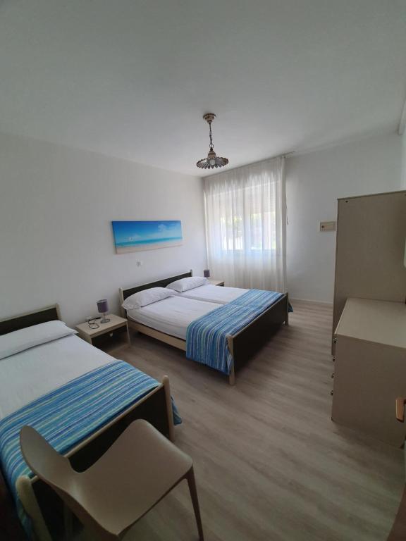 ein Schlafzimmer mit 2 Betten und einem Stuhl darin in der Unterkunft Residenza Canova in Lignano Sabbiadoro
