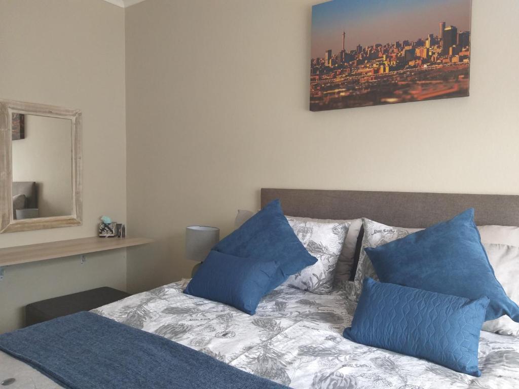 a bedroom with a bed with blue pillows on it at Burban Bliss in Johannesburg