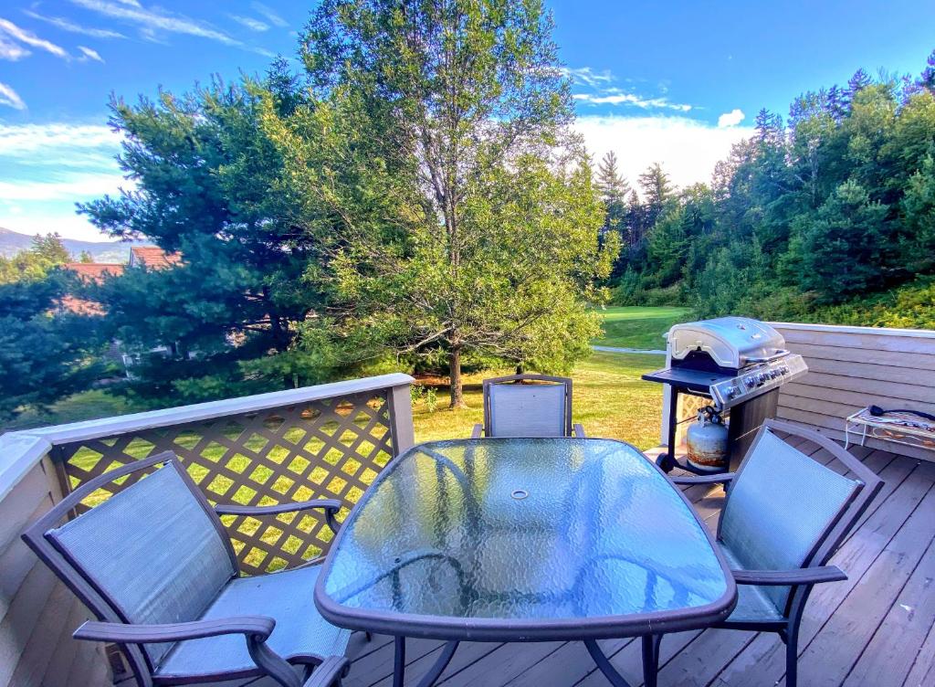 een tafel en stoelen op een terras met een grill bij F6 Townhome with golf course and mountain views in Bretton Woods next to Mt Washington HotelF6 in Carroll
