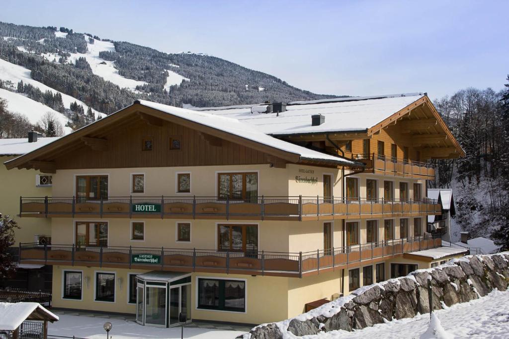 un grand bâtiment avec de la neige au-dessus dans l'établissement Hotel Bärenbachhof - Joker card included in summer, à Saalbach-Hinterglemm