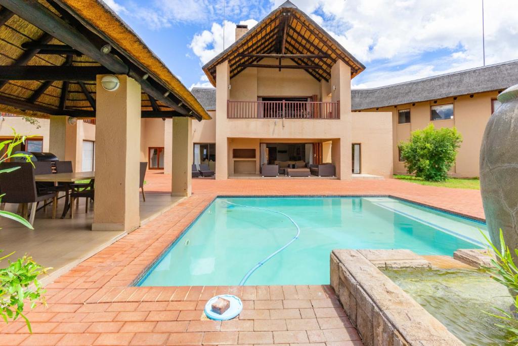 a swimming pool in front of a house at Waterberg House at Zebula - 8 adults and 4 kids in Mabula