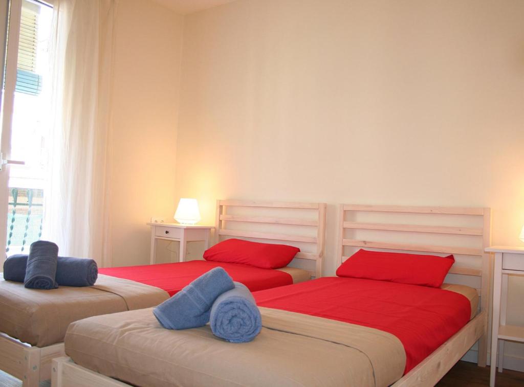 two beds in a bedroom with red and blue pillows at Piquer in Barcelona