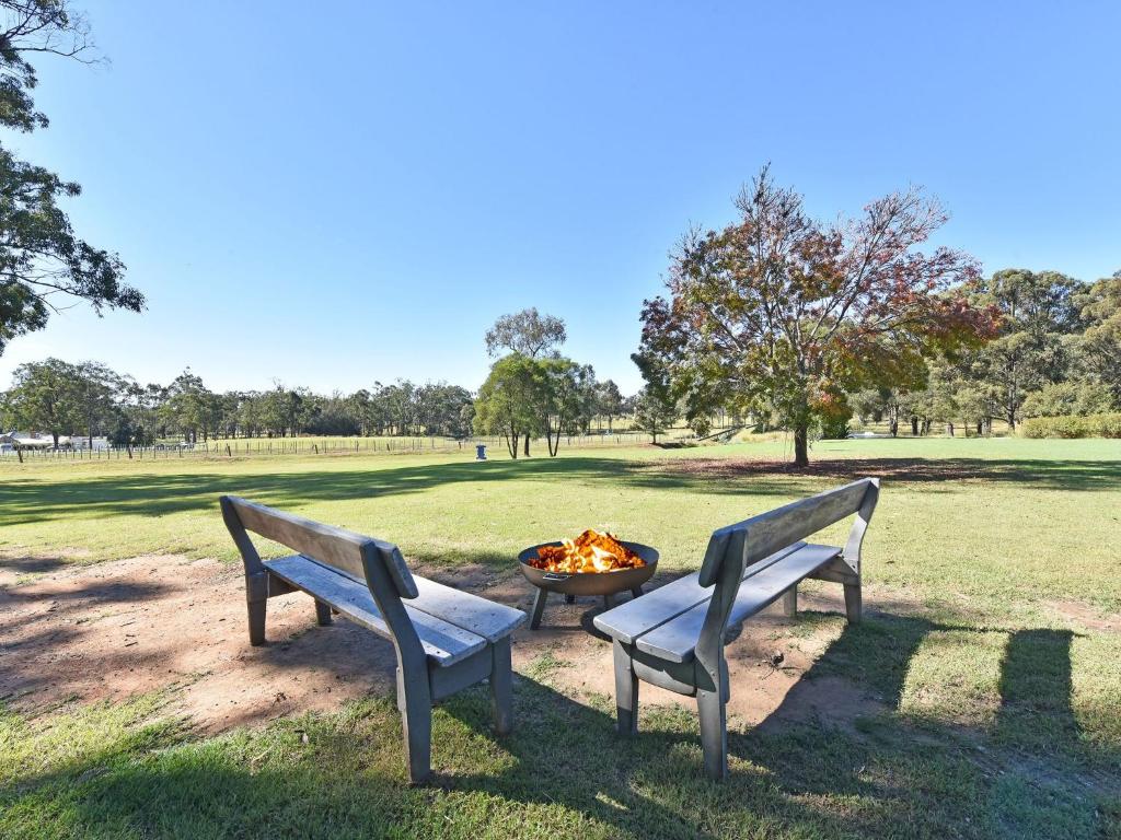 two benches sitting next to a fire pit in a park at Blaxlands Homestead - Nothing is closer opposite Hope Estate with Wifi and Pool plus Fireplace in Pokolbin