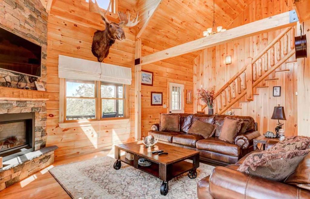 ein Wohnzimmer mit einem Sofa und einem Kamin in der Unterkunft OE Beautiful modern log home on 17 acres private views fire pit Ping Pong AC in Whitefield