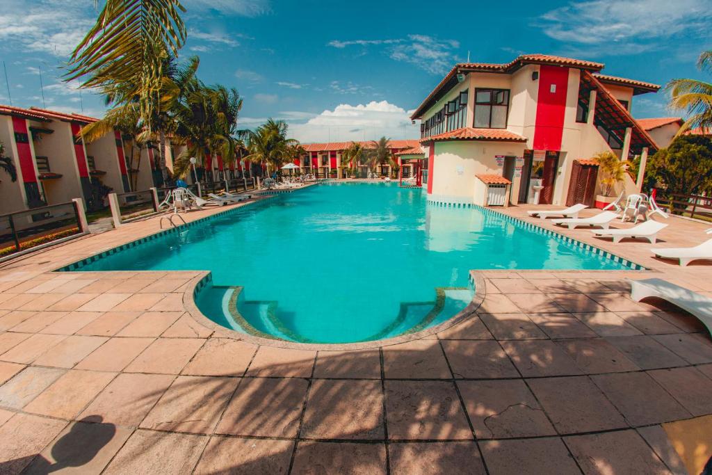 a swimming pool in a resort with palm trees and buildings at Casa Duplex 3 Suítes em Condomínio in Porto Seguro