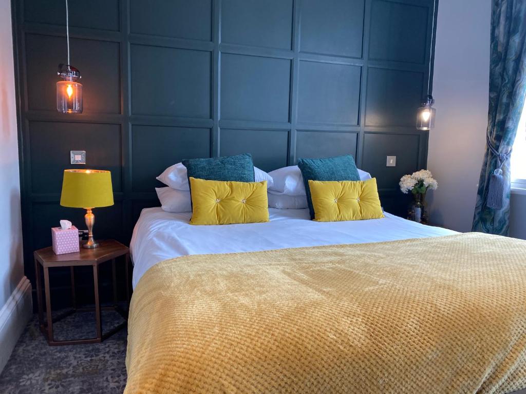 a bedroom with a large bed with yellow and blue pillows at The Bootham Tavern - York in York