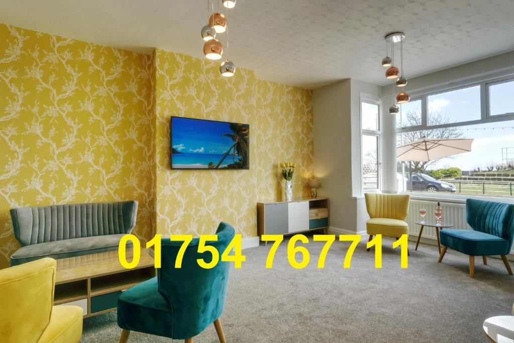 a living room with a couch and chairs and a tv at Palm Court, Seafront Accommodation in Skegness