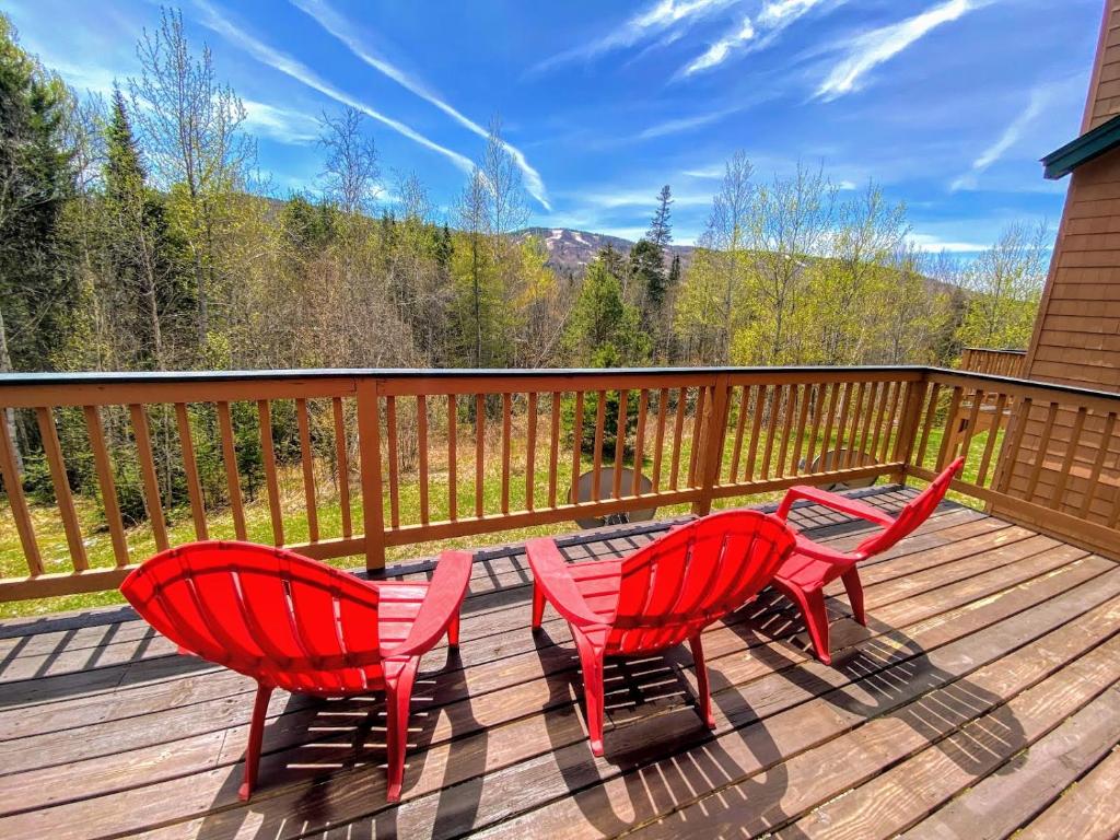 zwei rote Stühle und ein Tisch auf einer Terrasse in der Unterkunft W8 Mount Washington Place Townhome great slope views fireplace large deck yard and ping pong in Carroll