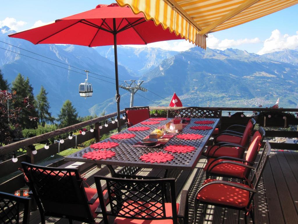 a table with chairs and an umbrella on a balcony at Chalet Lisa Ski-in, ski-out Well equipped in Nendaz