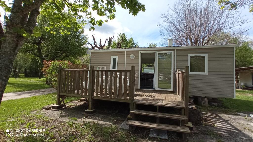 a tiny house with a porch and a deck at Camping LE Moulin in La Motte-Chalançon
