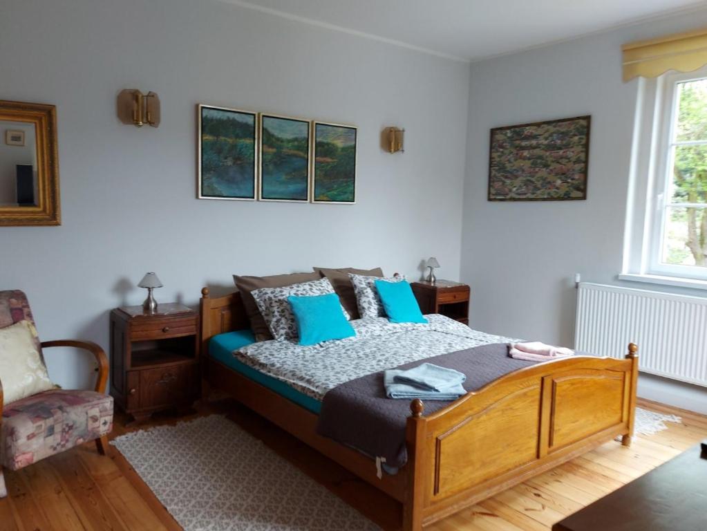 sypialnia z łóżkiem z niebieskimi poduszkami i krzesłem w obiekcie Apartament na Rybnej w Polanicy Zdroju