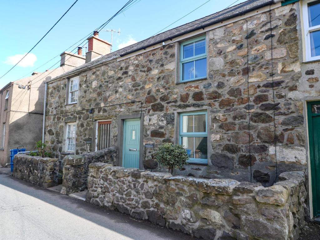 una vieja casa de piedra con una puerta azul en una calle en Ferndale, en Pwllheli