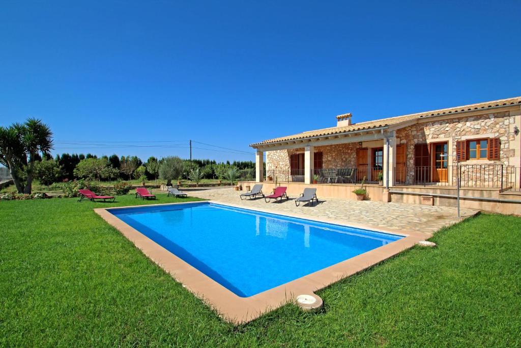 a villa with a swimming pool in front of a house at Can Roca in Felanitx