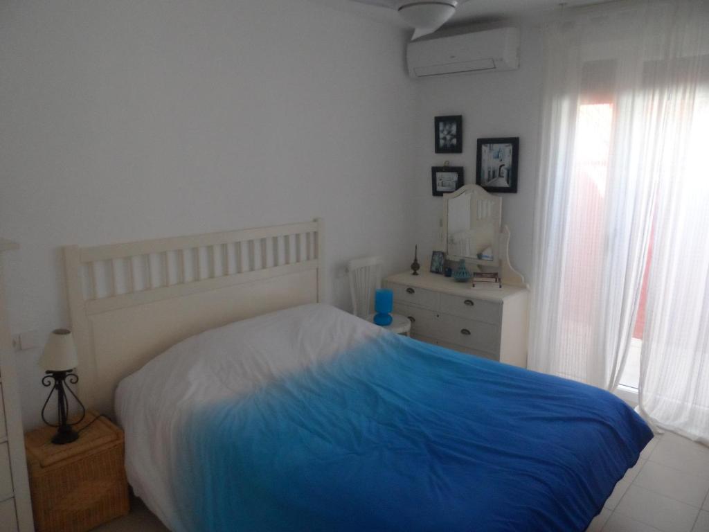biała sypialnia z niebieskim łóżkiem i oknem w obiekcie Apartamento encantador w mieście Las Negras