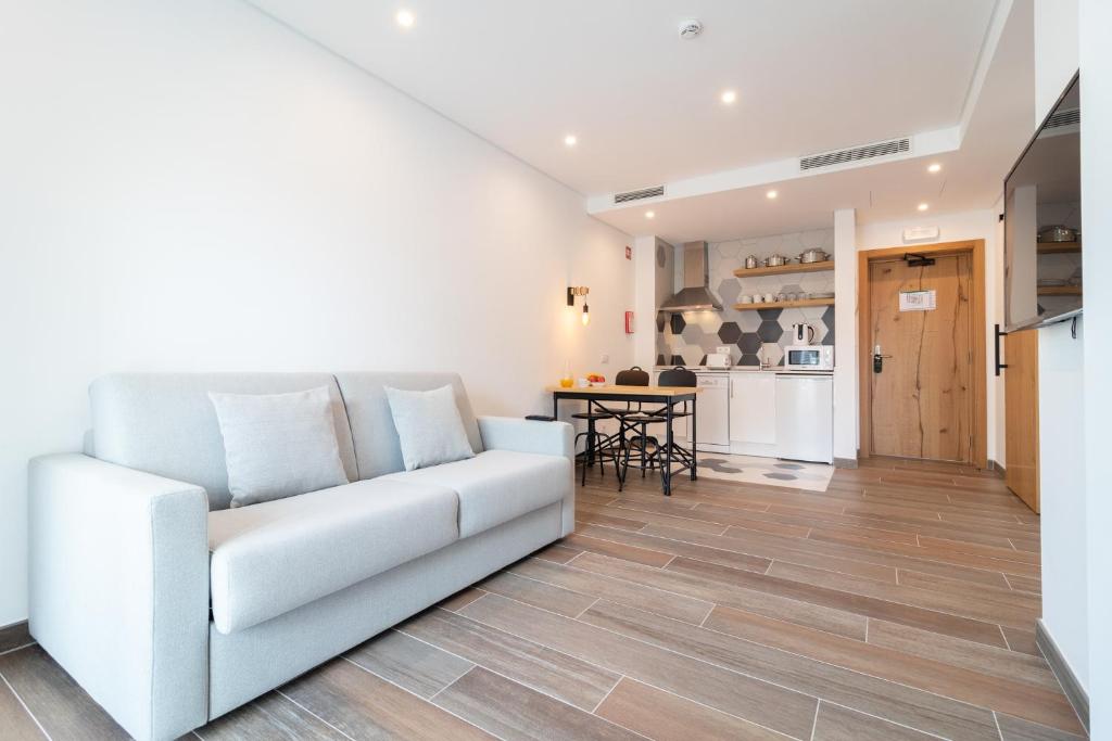 a living room with a white couch and a kitchen at Roots Hotel in Faro