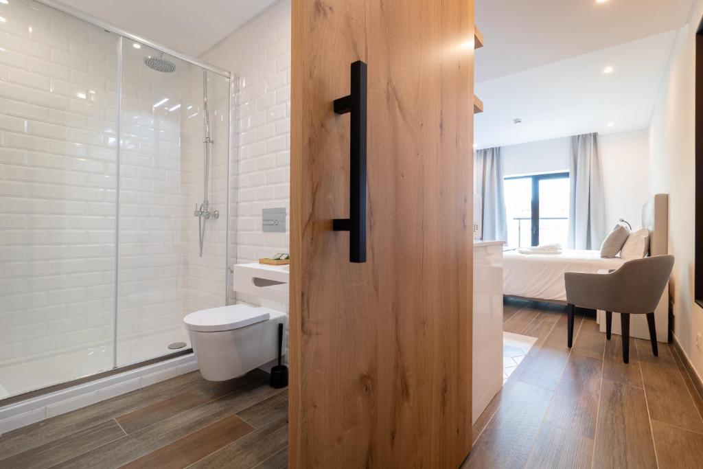 a bathroom with a toilet and a glass shower at Roots Hotel in Faro