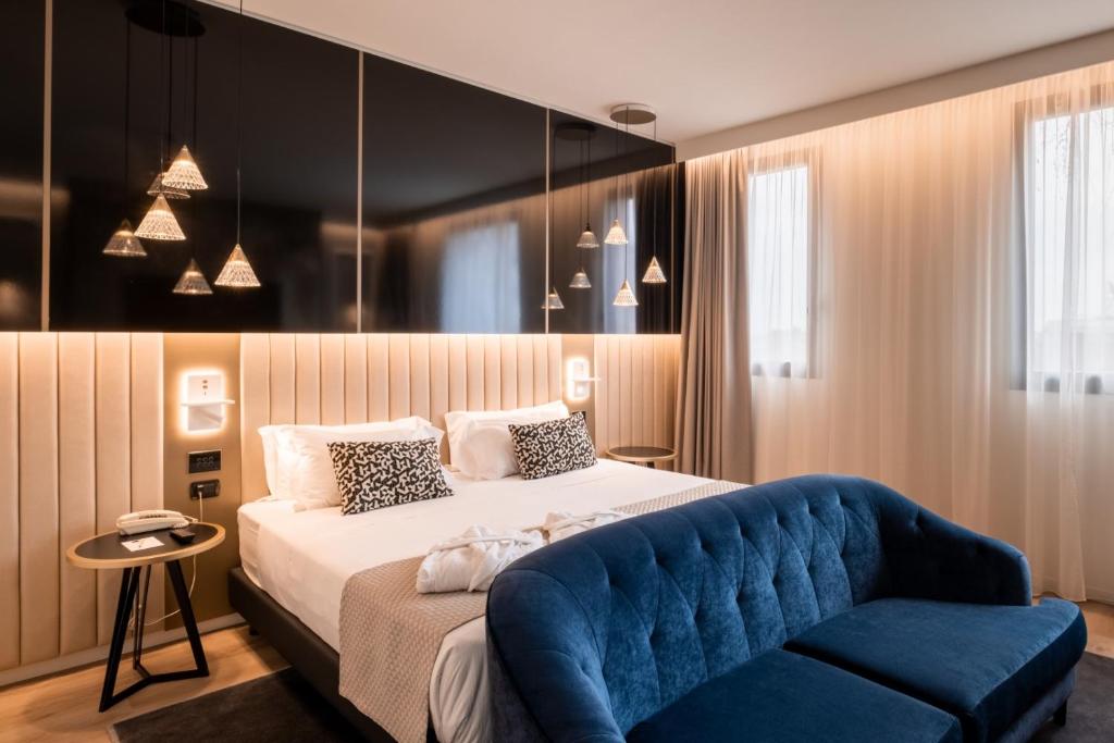 een slaapkamer met een bed en een blauwe bank bij Aemilia Hotel Bologna in Bologna