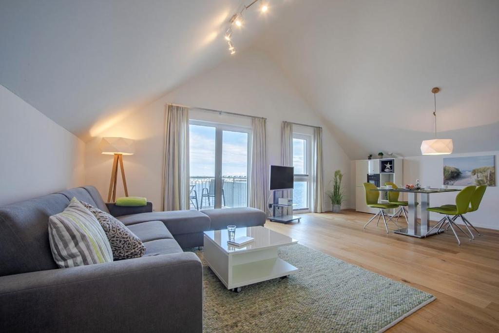 a living room with a couch and a table at Fewo Reeder's Topp by Seeblick Ferien ORO, Penthouse,Panoramablick,Sauna in Olpenitz