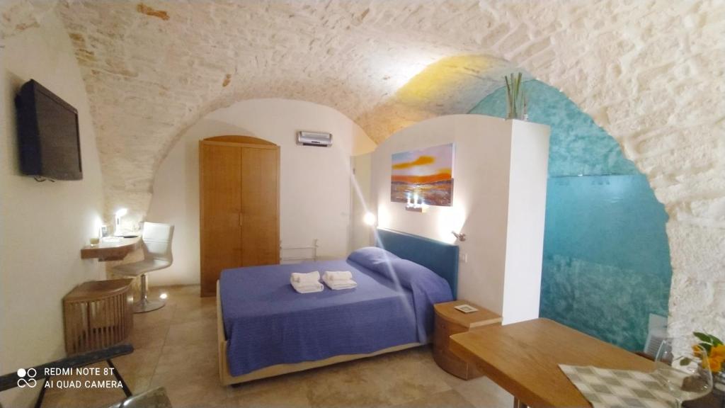 een slaapkamer met een blauw bed en een schilderij aan de muur bij La Volta del Conte-Holiday Home Centro Storico in Cisternino