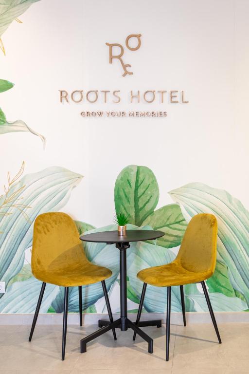 two chairs and a table in front of a wall at Roots Hotel in Faro