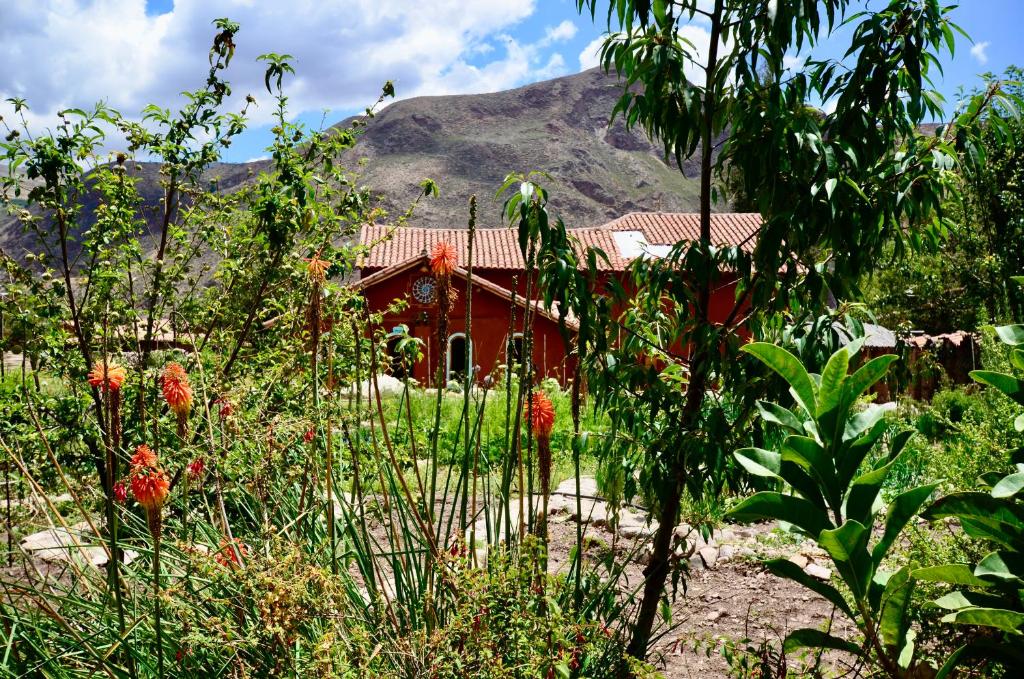 a red house with a mountain in the background at Kinsapacha Eco Lodge Farm in Urubamba
