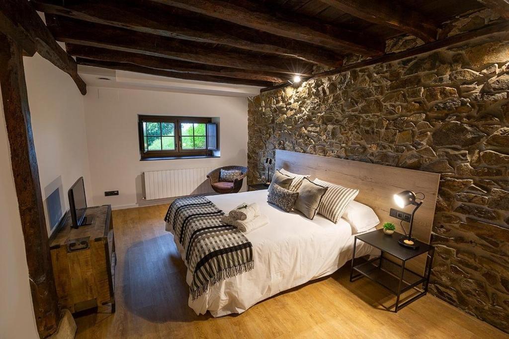 um quarto com uma cama grande e uma parede de pedra em ARBELA Apartamentuak em Aia
