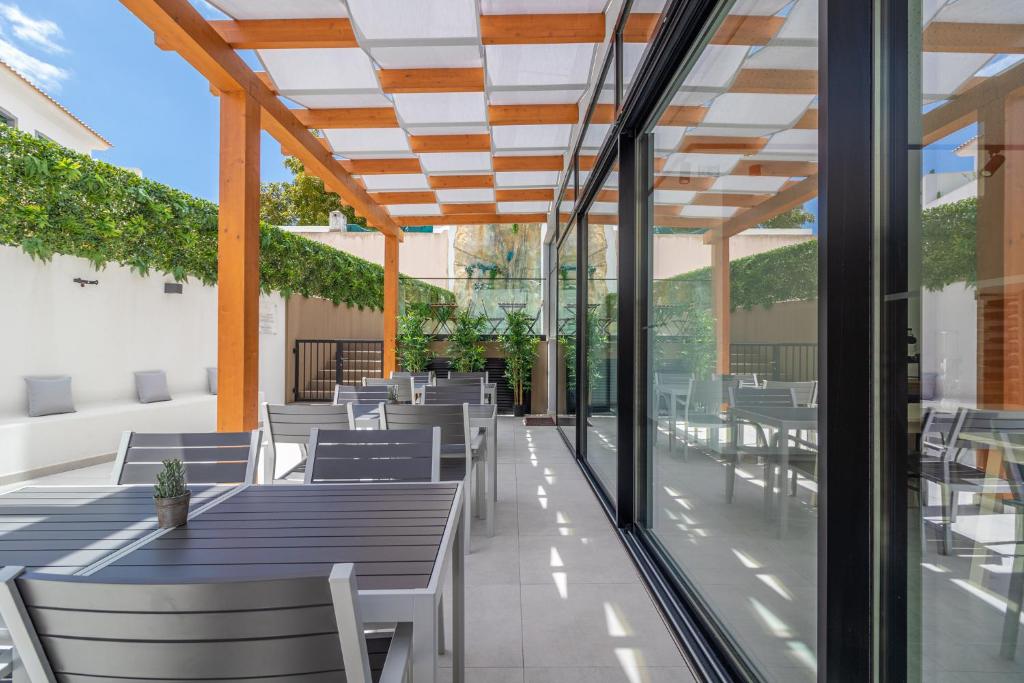 an outdoor patio with tables and chairs and windows at Roots Hotel in Faro