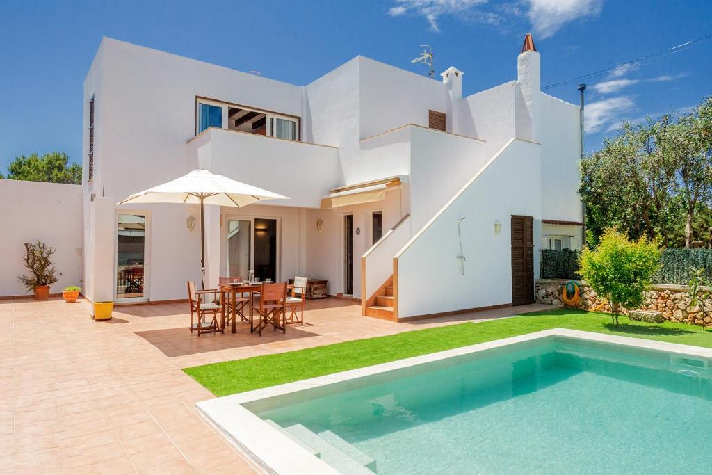 a villa with a swimming pool in front of a house at Villa Payu in Ciutadella