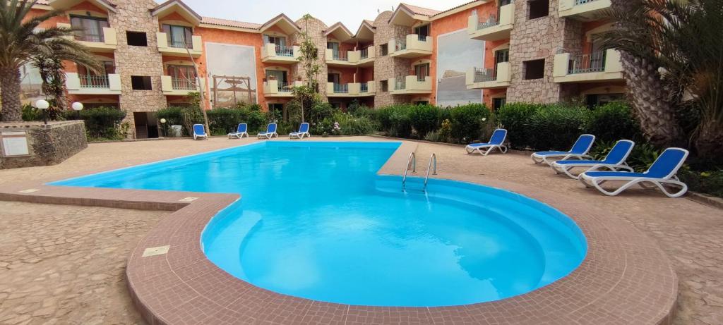uma grande piscina com cadeiras e um edifício em Sal Service djasal residence with pool em Santa Maria
