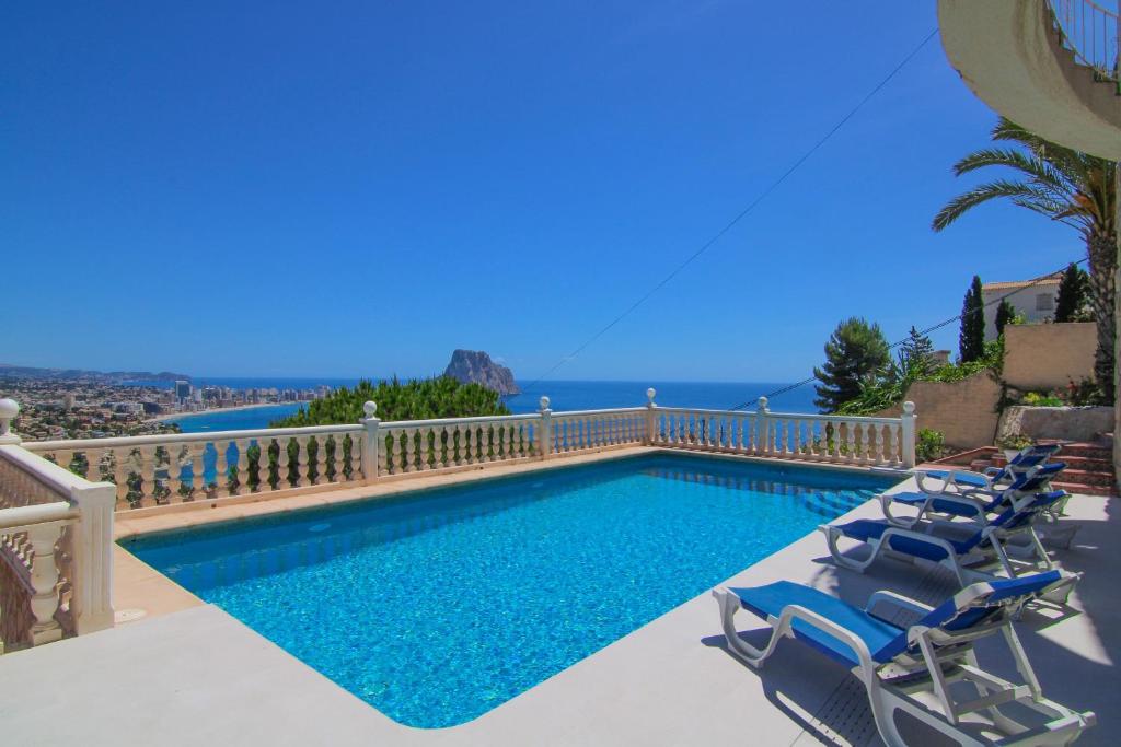 a swimming pool with chairs and the ocean in the background at Villa con piscina y vistas al mar - Mar 27 H in Calpe