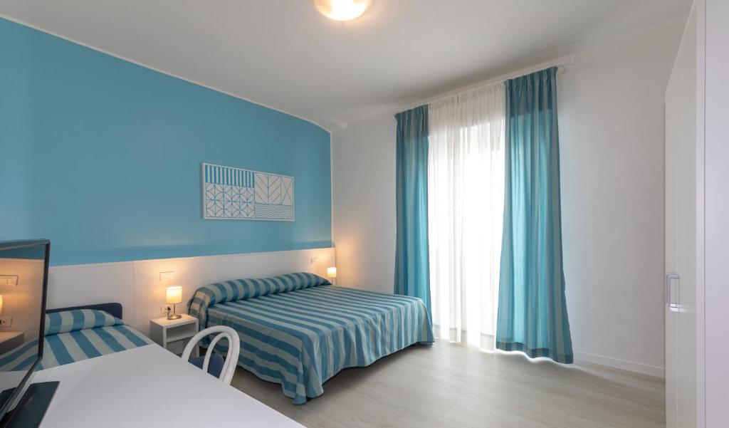 a bedroom with a bed and a window with blue walls at Hotel Paolina in Lido di Jesolo
