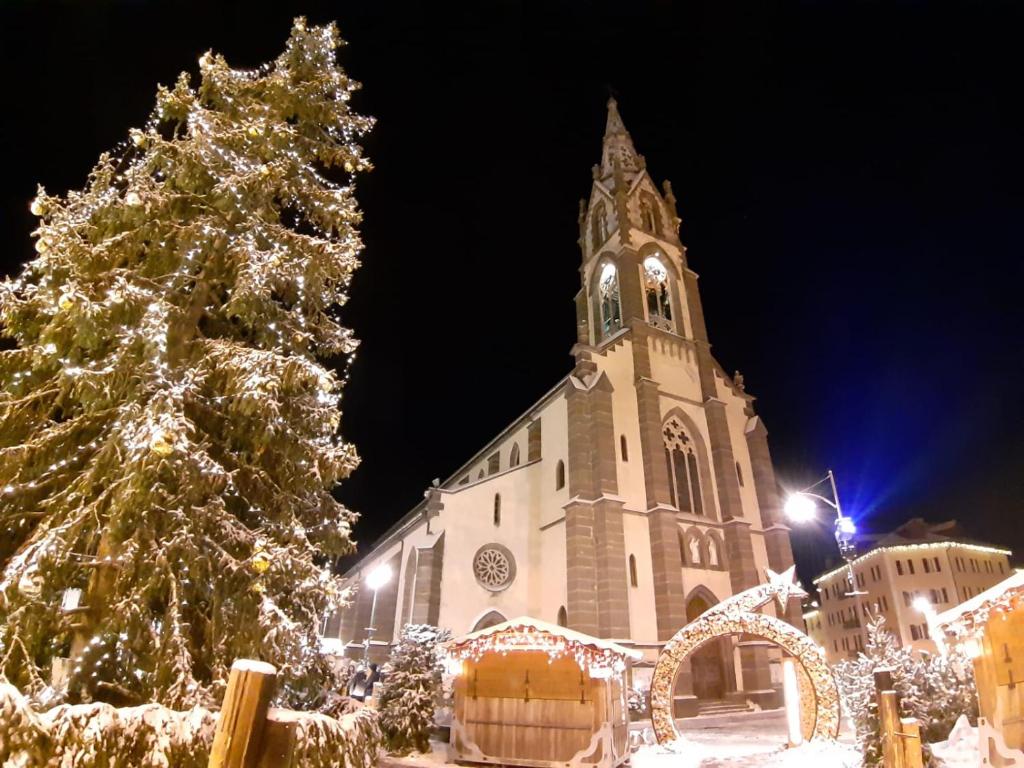 a church with a christmas tree in front of it at Le Bifore in valle in Predazzo