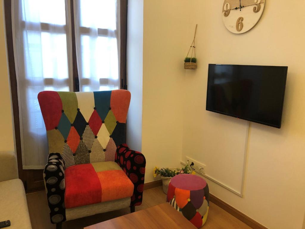 een woonkamer met een stoel en een flatscreen-tv bij ApartamentosArturo Llanes F LaPlaza in Llanes