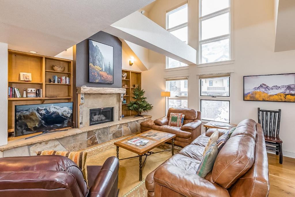 a living room with leather furniture and a stone fireplace at Blue Mesa 6 - Snow Down in Telluride