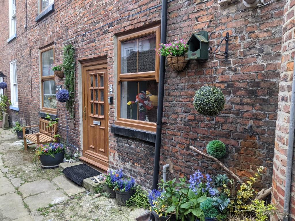 a brick building with a door and some plants at Endeavour Cottage Whitby sleeps 6 in Whitby