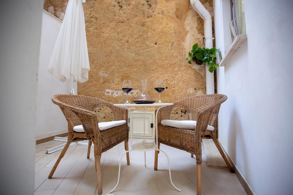 a table with two chairs and two glasses of wine at Alcova di relax in Castellammare del Golfo