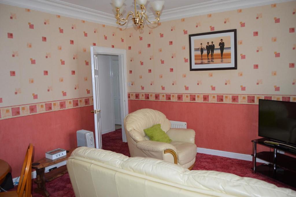 a living room with a white couch and a television at Kirk View holiday apartment in Kirkcaldy