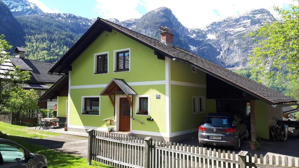 ein grünes und gelbes Haus mit einem Zaun in der Unterkunft Haus Pilz in Obertraun