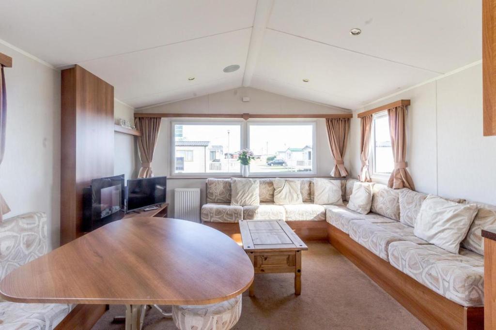 een woonkamer met een bank en een tafel bij Caledonia Summertime in Jaywick Sands