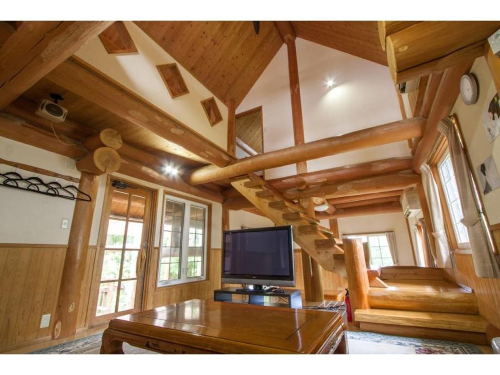 a living room with a tv and wooden ceilings at Log house for 12 people - Vacation STAY 35071v in Minamioguni