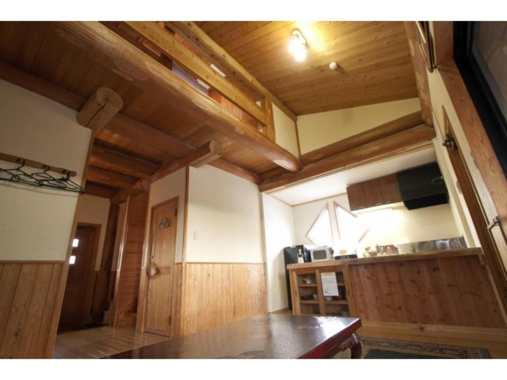 Log house for 12 people - Vacation STAY 35069v في ميناميوغوني: مطبخ بجدران خشبية وطاولة في الغرفة