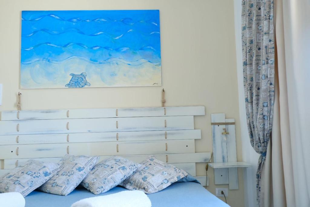 Una cama con almohadas azules y una pintura encima. en B&B Una favola di mare en Lampedusa