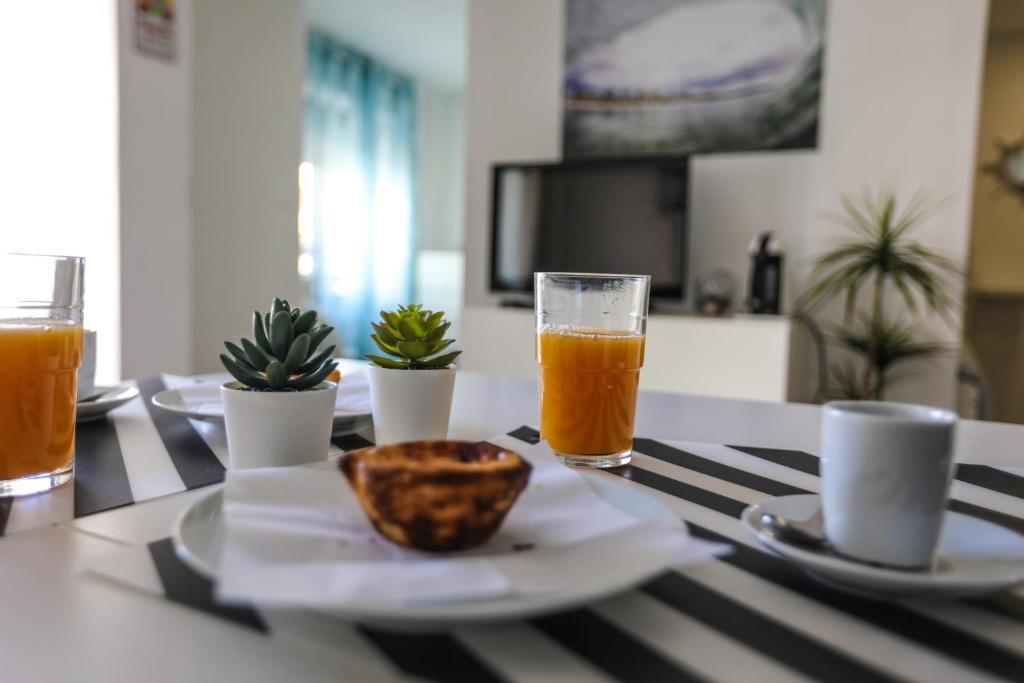 una mesa con un vaso de zumo de naranja y un tazón en Vina's Beach House - 2 minute walk to the beach, en Costa da Caparica