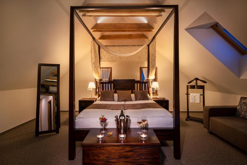 a bedroom with a bed and a table with glasses on it at Hotel Bílý jednorožec in Třeboň