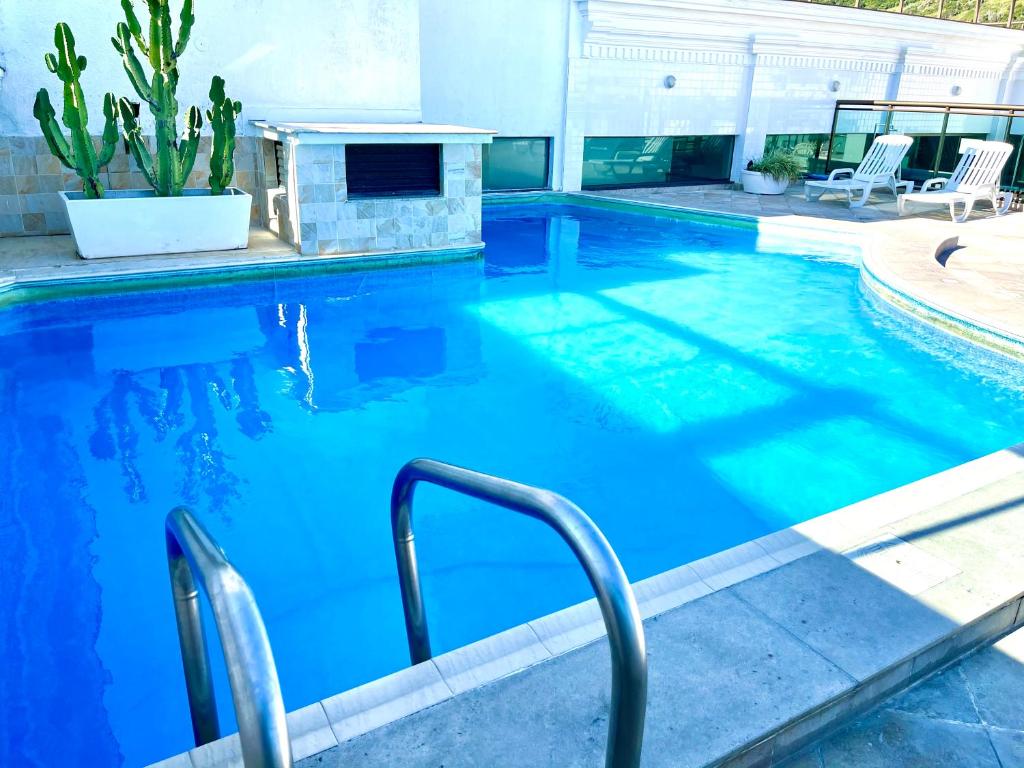 uma piscina com água azul numa casa em LOFT LUXO VISTA MAR PRAINHA até 5 PESSOAS em Arraial do Cabo