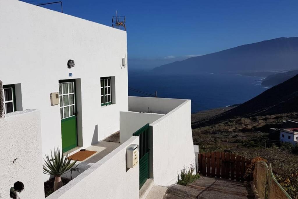 un edificio blanco con puertas verdes y vistas al océano en Casita Abuela Rosa en Sabinosa