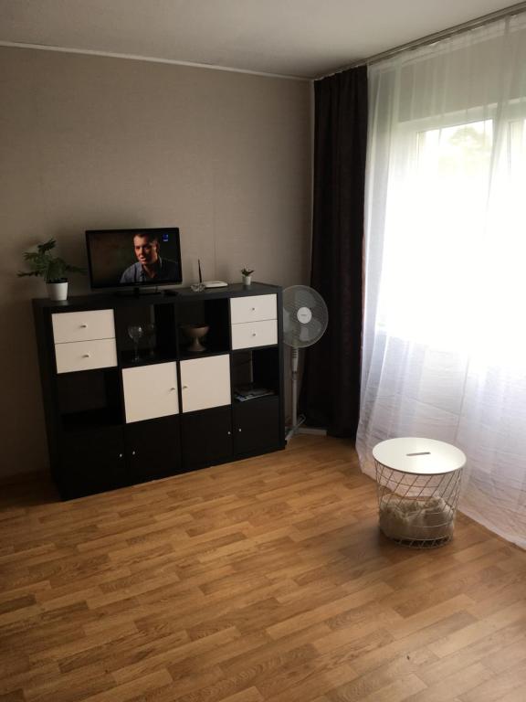 una sala de estar con TV en un armario y una ventana en sunny apartment, en Ventspils